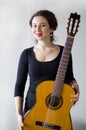 Beautiful girl sitting with a guitar on a white background, portrait