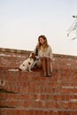 Beautiful girl is sitting with her dog Cavalier King Charles Spaniel on the red brick stairs Royalty Free Stock Photo