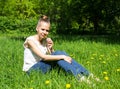 Beautiful girl sitting on the lawn with a dandelion Royalty Free Stock Photo