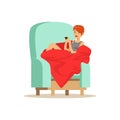 Beautiful girl sitting on a light blue armchair wrapped in a red blanket Royalty Free Stock Photo