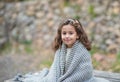 Beautiful girl is sitting on nature and is warming herself with a warm knitted blanket Royalty Free Stock Photo