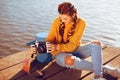 Beautiful girl sitting on the pier near the river. Beauty model with brunette hair. The girl at hot sunny day taking pictures old Royalty Free Stock Photo