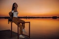 Beautiful girl sitting by the river and enjoy the beautiful sunset while waiting for someone Royalty Free Stock Photo