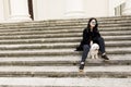 Beautiful girl sitting on stairs with her pet dog after walk in Royalty Free Stock Photo