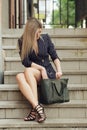 Beautiful girl sitting on stairs and looking for something in her bag Royalty Free Stock Photo