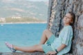 Beautiful girl sitting on a stone wall, in background is the blue sea, Budva, Montenegro. Royalty Free Stock Photo