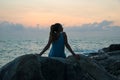 The beautiful girl sitting on stones and looking in a distance, the girl at sunset to meditate in silence, beautiful body. concept Royalty Free Stock Photo