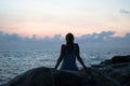 The beautiful girl sitting on stones and looking in a distance, the girl at sunset to meditate in silence, beautiful body. concept Royalty Free Stock Photo