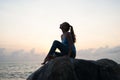 The beautiful girl sitting on stones and looking in a distance, the girl at sunset to meditate in silence, beautiful body. concept Royalty Free Stock Photo