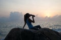 The beautiful girl sitting on stones and looking in a distance, the girl at sunset to meditate in silence, beautiful body. concept Royalty Free Stock Photo