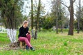 Beautiful girl sitting on stump in the park with your smartpho Royalty Free Stock Photo