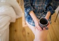 Beautiful girl is sitting on swing in loft minimalist interior. Young woman in men`s checkered shirt is drinking coffee. Cozy Royalty Free Stock Photo