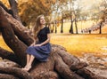 Beautiful girl sitting on the tree in the autumn landscape Royalty Free Stock Photo