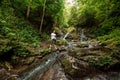 Beautiful girl at a small waterfall, Carpathian mountain stream. Travel concept, leisure activity, vacation