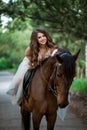 beautiful girl in elegant dress sits on horseback and smiles Royalty Free Stock Photo