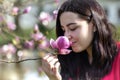 Beautiful girl smelling the flowers. Blossoming magnolia in the park garden. Royalty Free Stock Photo