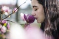 Beautiful girl smelling the flowers. Blossoming magnolia in the park garden. Royalty Free Stock Photo