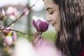 Beautiful girl smelling the flowers. Blossoming magnolia in the park garden. Royalty Free Stock Photo