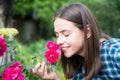 Beautiful girl smelling a rose flower in spring park. Young woman in flowering garden with roses. Beauty model with