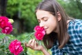 Beautiful girl smelling a rose flower in spring park. Young woman in flowering garden with roses. Beauty model with