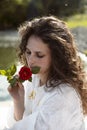 Beautiful girl smells rose flowers in her hands. Woman in a white dress. Royalty Free Stock Photo