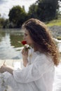 Beautiful girl with rose flowers in her hands. Woman in a white dress. Closeup profile portrait. Royalty Free Stock Photo