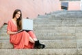 Beautiful girl smiling using a laptop on the stairs Royalty Free Stock Photo