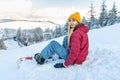 Beautiful girl snowboarder sitting alone in the snow on hill mountain outdoor, winter sport activity Royalty Free Stock Photo