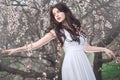 Beautiful girl standing at blossoming tree in the garden