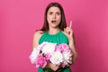 Beautiful girl standing with bouquet of rosy and white peonies in hands, pointing with her index finger up, isolated on pink Royalty Free Stock Photo