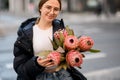 Beautiful girl standing in the street with bouquet of pink Protea flowers Royalty Free Stock Photo