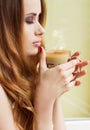 Beautiful girl standing at the window with a hot Cup of invigorating coffee early in the morning Royalty Free Stock Photo