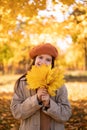 A beautiful girl standing with yellow maple leaves in autumn park, gorgeous hair, a teenager smiles and looks at the Royalty Free Stock Photo