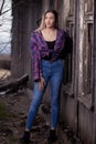 A beautiful girl stands in front of an old wooden window