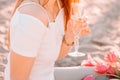 .beautiful girl stands on a sandy beach with a bottle of champagne. romantic walk at dawn with the rays of the sun . Royalty Free Stock Photo