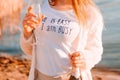 .beautiful girl stands on a sandy beach with a bottle of champagne. romantic walk at dawn with the rays of the sun . Royalty Free Stock Photo