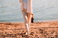 beautiful girl stands on a sandy beach with a bottle of champagne. romantic walk at dawn with the rays of the sun. Royalty Free Stock Photo