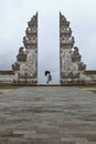 Beautiful Girl Stands On Tiptoes Near Gates Of Heaven In Pura Lempuyang Temple In Bali, Indonesia.