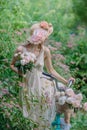 A beautiful girl in a straw hat decorated with roses with a mint colored bicycle in the garden