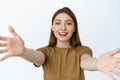 Beautiful girl stretching out hands and smiling, reaching for hug or to hold something in her arms, standing in t-shirt Royalty Free Stock Photo