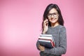 Beautiful girl student with books talking on phone on pink background Royalty Free Stock Photo