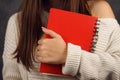 Beautiful girl student in a sweater with a red notebook on a dark backgroundred notebook in the hands of a girl