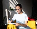 Beautiful girl student writes with a pen an assignment in a notebook while sitting on an armchair in a cafe Royalty Free Stock Photo