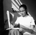 Beautiful girl student writes with a pen an assignment in a notebook while sitting on an armchair in a cafe Royalty Free Stock Photo