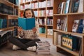 Beautiful girl is studying reading a book while standing on the floor among books in the bookshop