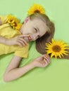 A beautiful girl with sunflowers in her blonde hair and a yellow baby manicure Royalty Free Stock Photo