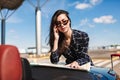 Beautiful girl in sunglasses leaning on car thoughtfully looking road on map with airport on background Royalty Free Stock Photo