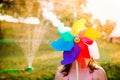 Beautiful girl in swimsuit hiding behind pinwheel, summer garden