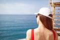 A beautiful girl with long hair and a white cap looks at the blue sea Royalty Free Stock Photo