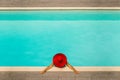 Beautiful girl in a swimsuit and a red hat in a blue water pool Royalty Free Stock Photo